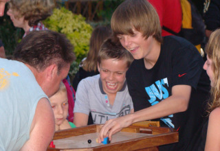 Kinderen en volwassenen spelen samen een gezelschapsspel op Camping Seasonova Le Point du Jour in Normandië.