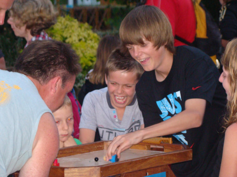 Niños y adultos juegan un juego de mesa al aire libre en Camping Seasonova Le Point du Jour, Normandía, Francia.