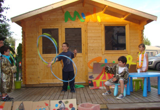 Kinderen brengen een voorstelling voor een houten hut bij Camping Seasonova Le Point du Jour in Normandië.