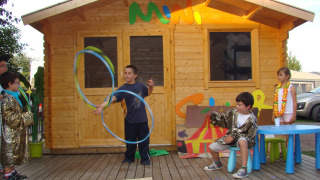 Des enfants jouent et font un spectacle devant un chalet au Camping Seasonova Le Point du Jour en Normandie.