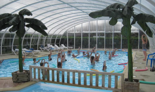 Piscina cubierta con clase de aeróbic acuático en Camping Seasonova Le Point du Jour en Normandía, Francia.