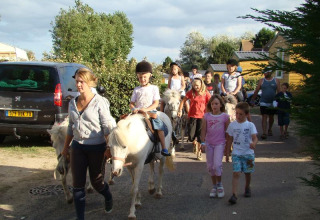 Bambini a cavallo di pony accompagnati da adulti al Camping Seasonova Le Point du Jour in Normandia, Francia.