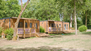 Casette in legno al lodge Prestige Cottage, immerse tra alberi e natura in un'atmosfera rilassante.