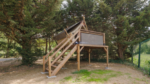 Tienda safari Nomad Bivouac en Camping Seasonova du Chêne, Francia, rodeada de árboles verdes.