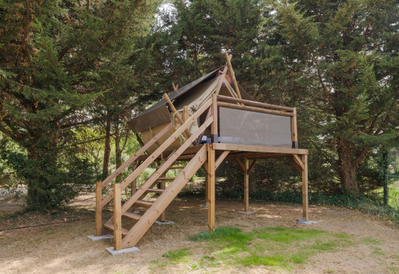 Nomad Bivouac safaritent bij Camping Seasonova du Chêne in Frankrijk, omringd door groene bomen.
