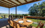 Terraza de madera con mesa puesta y vistas verdes en Cottage Premium, Domaine Seasonova Saâne et Mer, Francia.