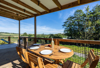 Terraza de madera con mesa puesta y vistas verdes en Cottage Premium, Domaine Seasonova Saâne et Mer, Francia.