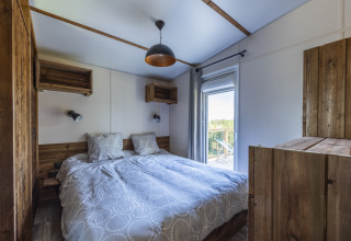 Dormitorio en Cottage Premium de Domaine Seasonova Saâne et Mer, Francia, con muebles de madera y balcón.