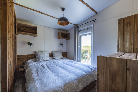 Dormitorio en Cottage Premium de Domaine Seasonova Saâne et Mer, Francia, con muebles de madera y balcón.