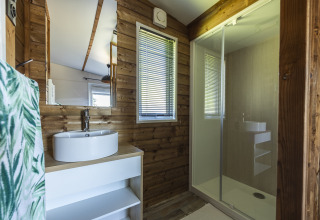 Baño moderno de cabaña de madera en Domaine Seasonova Saâne et Mer con lavabo redondo y ducha amplia.