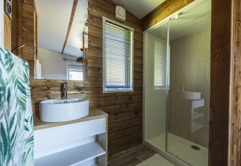 Modern wooden cottage bathroom at Domaine Seasonova Saâne et Mer with round sink, mirror, and shower.