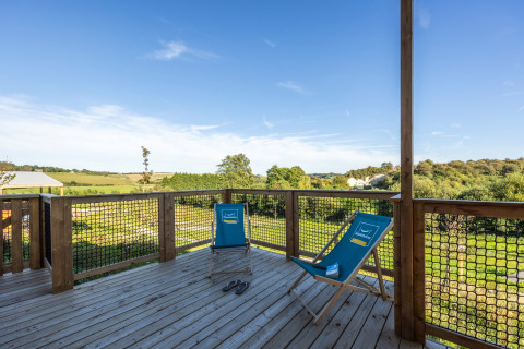Terraza de madera con dos tumbonas azules en Prestige Cottage en Domaine Seasonova Saâne et Mer, Francia.