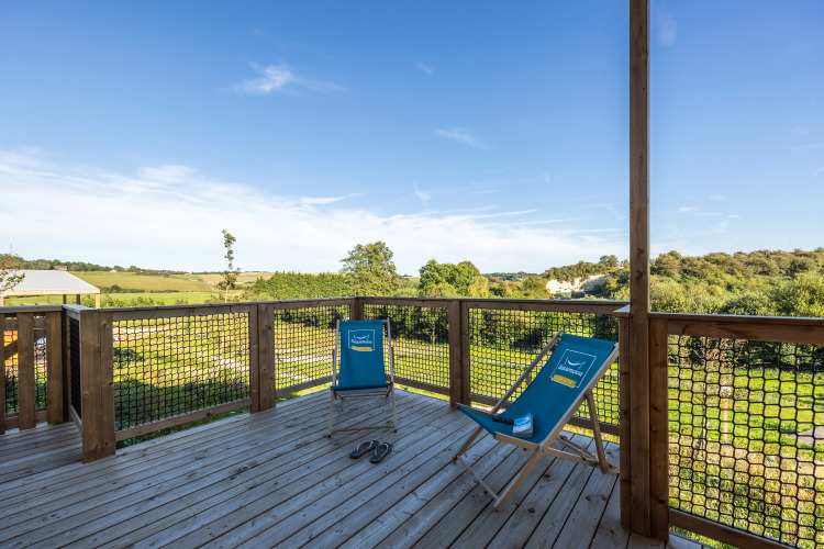 Wooden deck with two blue lounge chairs at Prestige Cottage, Domaine Seasonova Saâne et Mer, France.