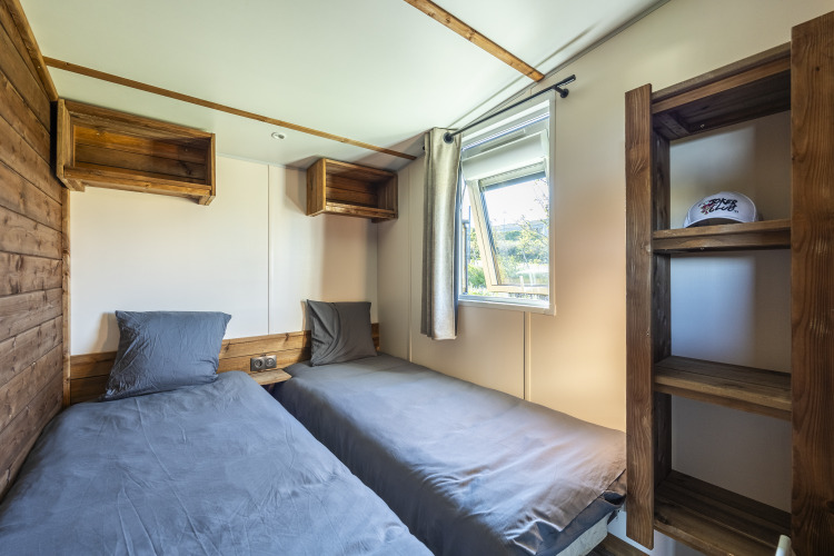 Habitación con dos camas individuales, estanterías de madera y ventana en Prestige Cottage, Domaine Seasonova Saâne et Mer en Francia.