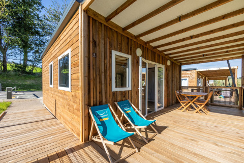 Terraza de la Casa Cottage PMR accesible, con suelo de madera, sillas y comedor exterior cubierto.
