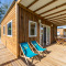 Houten veranda van Cottage PMR voor mindervaliden, met ligstoelen en buitentafel onder overkapping.