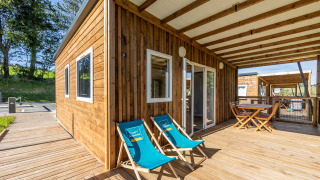 Barrierefreie Lodge Cottage PMR mit großer Holzterrasse, Liegestühlen und Sitzbereich im Freien.