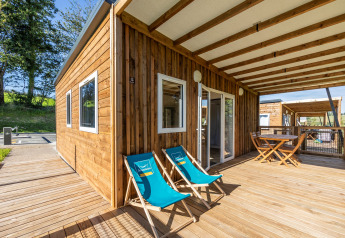 Accessible Cottage PMR lodge with a spacious wooden deck, lounge chairs, and outdoor dining area under roof.
