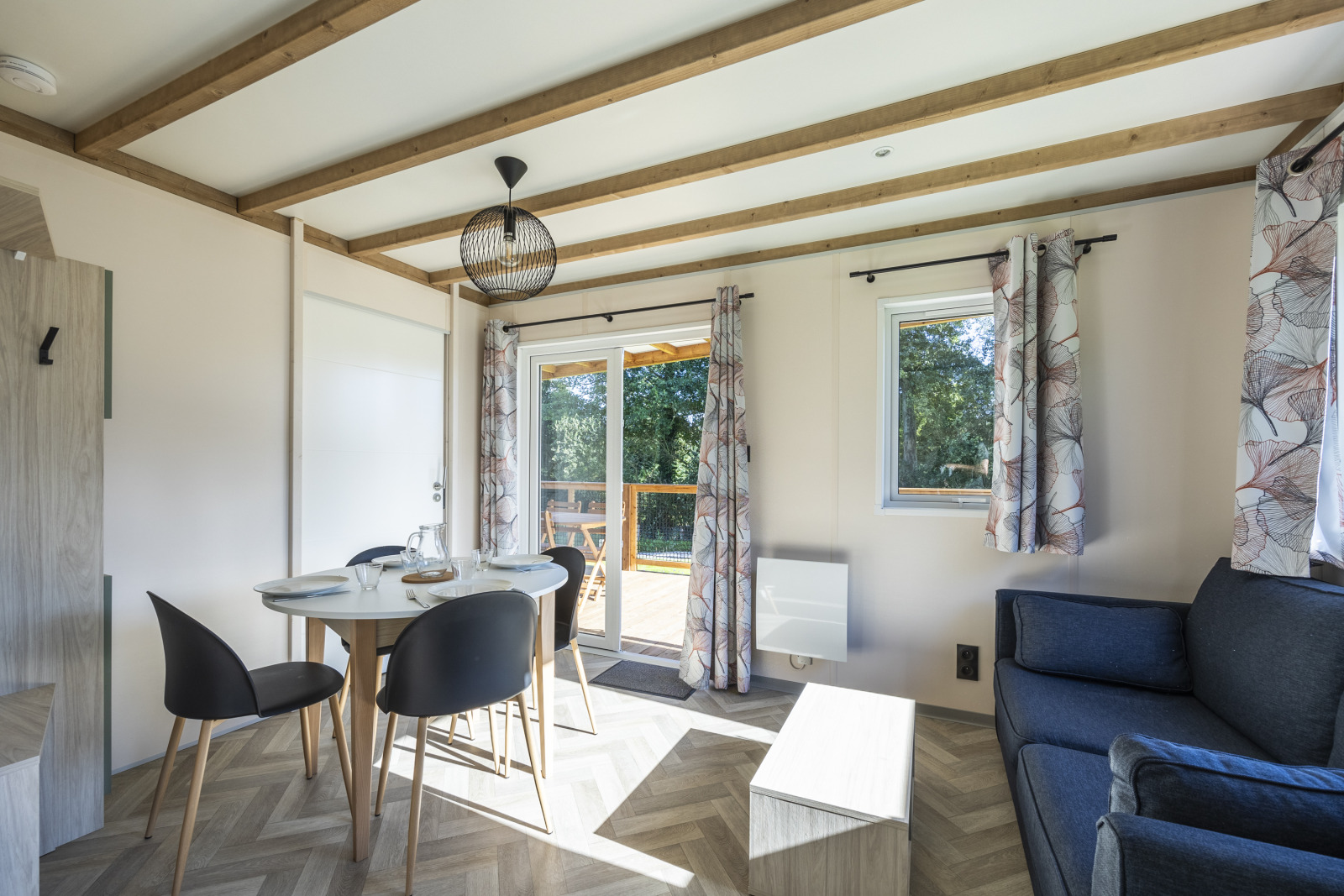 Licht interieur van een toegankelijke cottage met eettafel, stoelen en bank bij Domaine Seasonova Saâne et Mer.