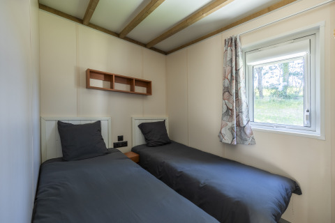Twee eenpersoonsbedden met donker beddengoed in een toegankelijke kamer in Cottage PMR, Domaine Seasonova Saâne et Mer.