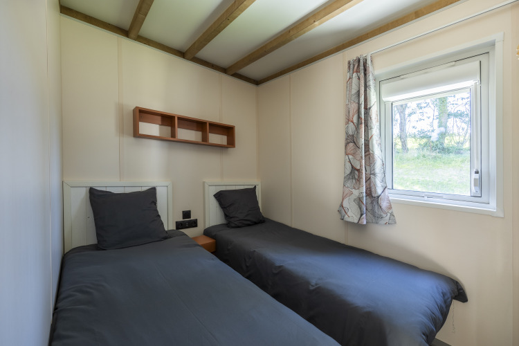 Deux lits simples avec une literie foncée dans une chambre PMR au Domaine Seasonova Saâne et Mer en France.