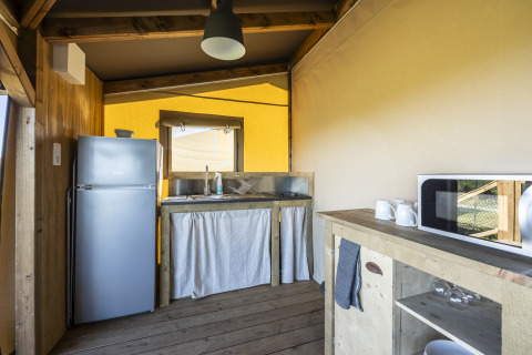 Zona de cocina dentro de la tienda safari Ecolodge en Domaine Seasonova Saâne et Mer, Francia, con nevera.