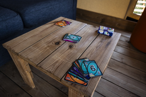 Cartes UNO dispersées sur une table en bois dans une tente safari à Domaine Seasonova Saâne et Mer, France.