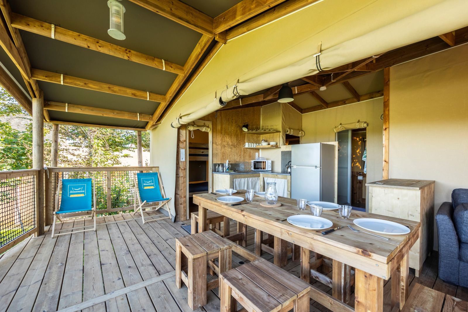 Interieur van een safaritent ecolodge bij Domaine Seasonova Saâne et Mer, met houten meubels en keuken.