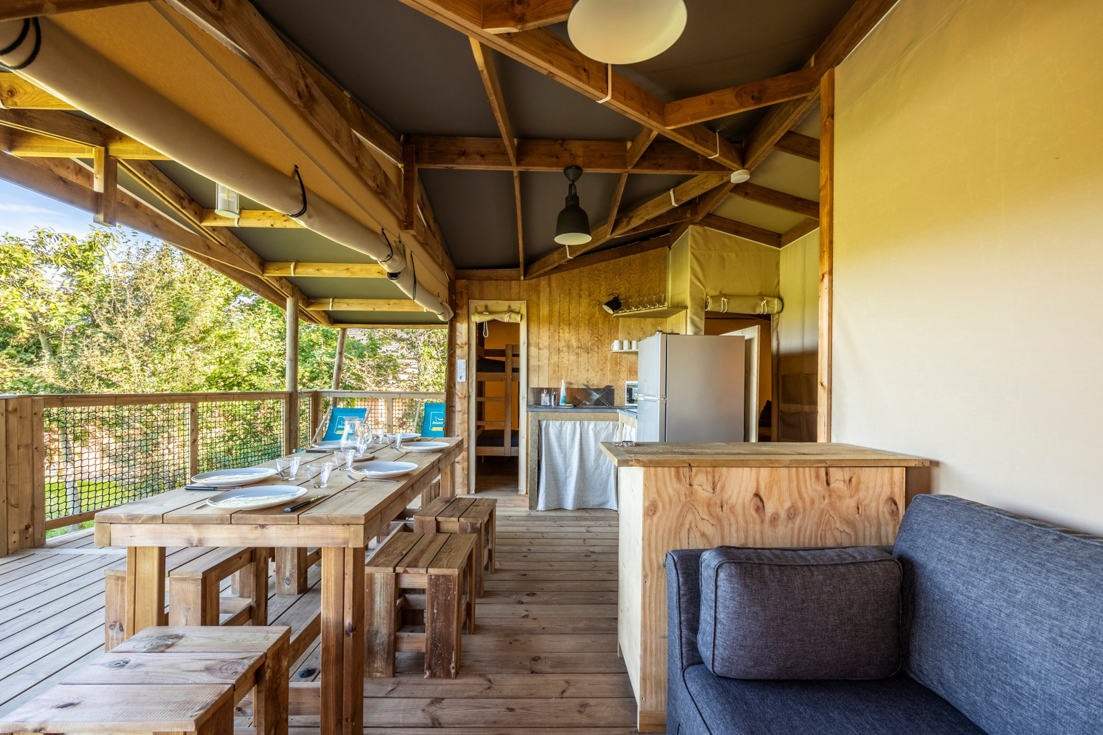Interieur van een luxe safari ecolodge tent met houten meubels bij Domaine Seasonova Saâne et Mer in Frankrijk.