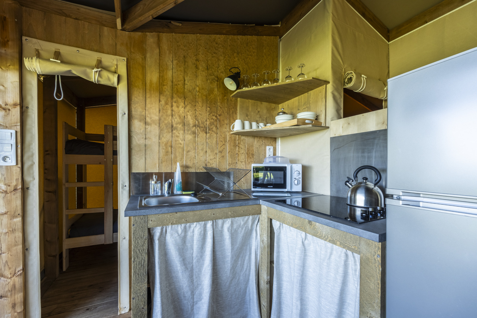 Keuken in safari tent Ecolodge bij Domaine Seasonova Saâne et Mer, met koelkast, magnetron en servies.