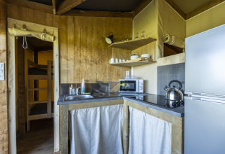 Cocina en tienda safari Ecolodge de Domaine Seasonova Saâne et Mer, con nevera, microondas y utensilios.