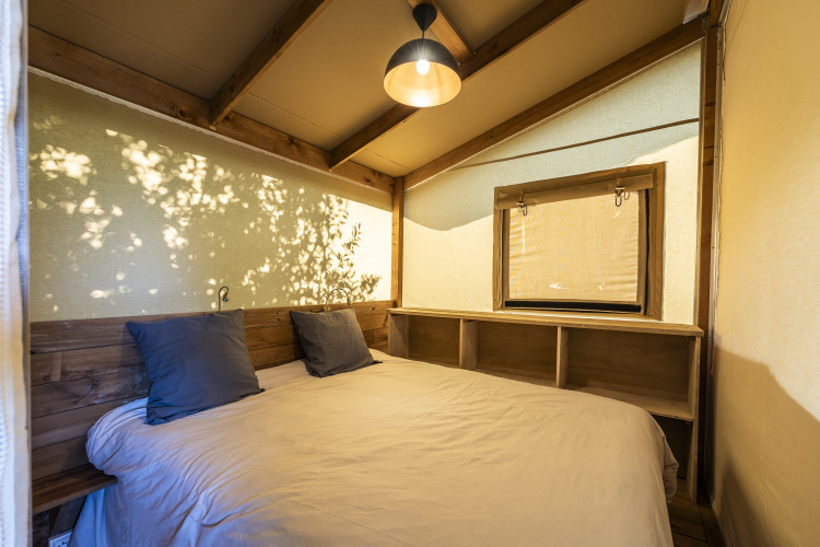 Dormitorio de la tienda safari Ecolodge en Domaine Seasonova Saâne et Mer, Francia, con decoración de madera.