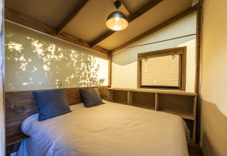 Dormitorio de la tienda safari Ecolodge en Domaine Seasonova Saâne et Mer, Francia, con decoración de madera.