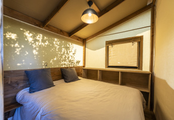 Dormitorio de la tienda safari Ecolodge en Domaine Seasonova Saâne et Mer, Francia, con decoración de madera.