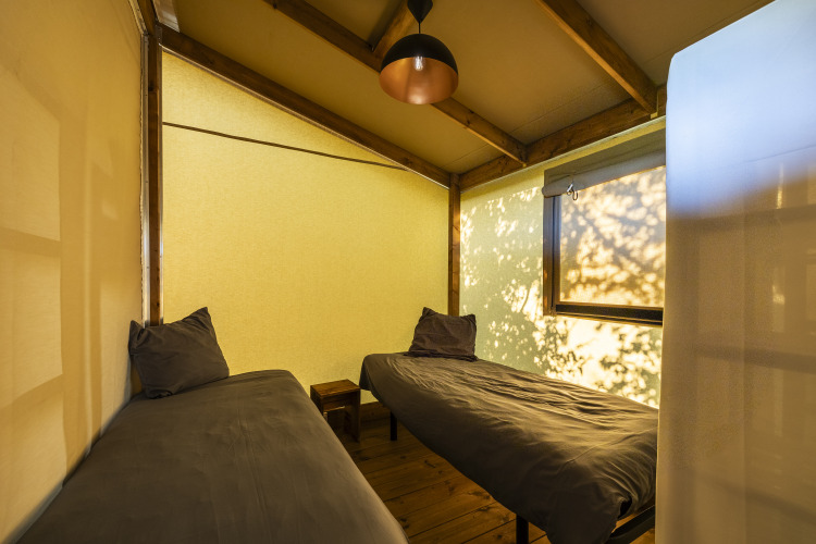 Interior de una tienda safari en Ecolodge Domaine Seasonova Saâne et Mer, Francia, con dos camas individuales.