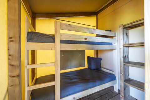 Interior de una tienda safari Ecolodge en Domaine Seasonova Saâne et Mer, Francia, con literas de madera.