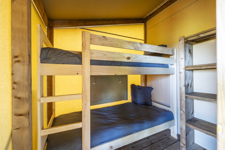 Interior de una tienda safari Ecolodge en Domaine Seasonova Saâne et Mer, Francia, con literas de madera.