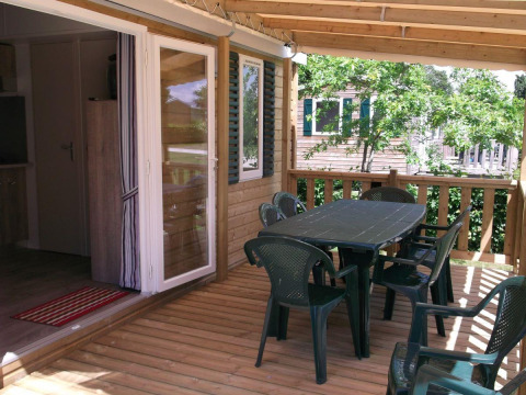 Houten terras met plastieken stoelen en tafel bij Cottage Zen, Camping Seasonova La Forêt, Frankrijk.