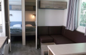 Interior of Cottage Zen at Camping Seasonova La Forêt, France, showing living area, two bedrooms, and sunlight.