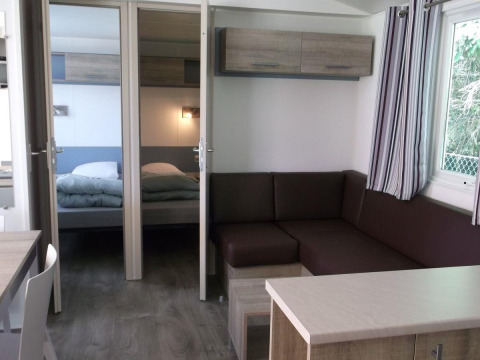 Innenraum des Cottage Zen im Camping Seasonova La Forêt, Frankreich, modern eingerichtet mit Sofa und Bett.