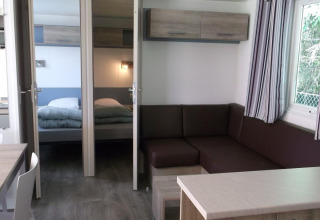 Innenraum des Cottage Zen im Camping Seasonova La Forêt, Frankreich, modern eingerichtet mit Sofa und Bett.