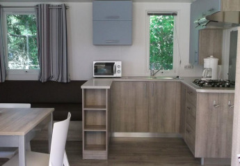 Cucina moderna e zona pranzo in una casetta Cottage Zen al Camping Seasonova La Forêt, con arredi in legno.