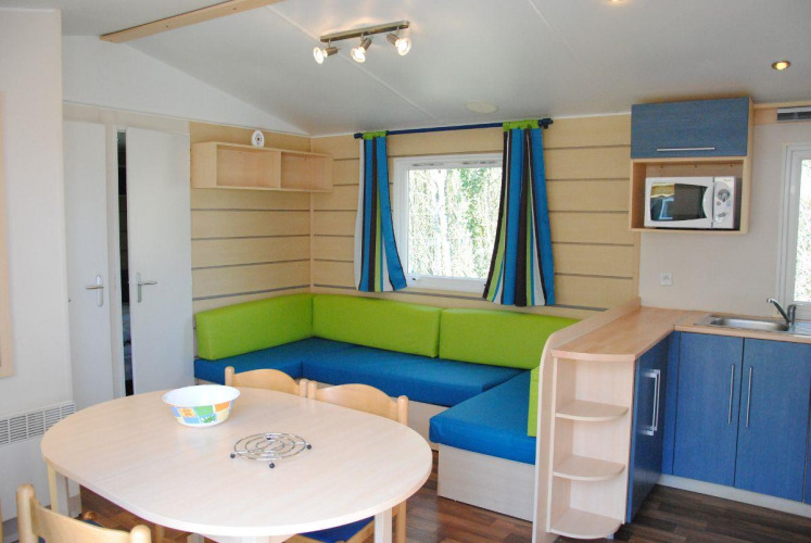 Sala moderna en la cabaña Cottage Zen en Camping Seasonova La Forêt, Francia, con cocina y mesa comedor.