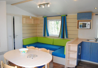 Zona giorno moderna nel Cottage Zen al Camping Seasonova La Forêt, Francia, con cucina e tavolo da pranzo.