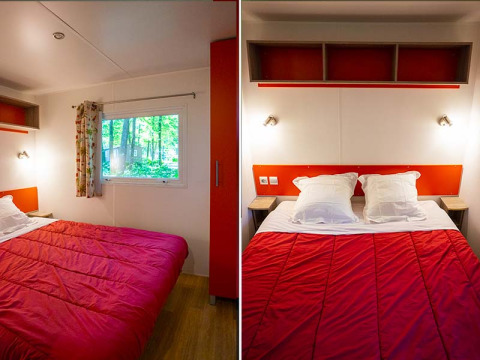 Slaapkamer in een Mobilodge safaritent bij Camping Seasonova La Forêt, Frankrijk, met rood dekbed.
