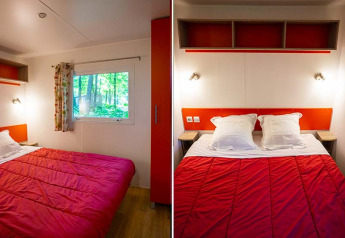 Camera da letto in una tenda safari Mobilodge al Camping Seasonova La Forêt, Francia, con piumone rosso.