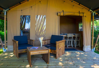 Tenda safari Slow Lodge al Camping Seasonova La Forêt in Francia, con terrazza in legno e sedie confortevoli.