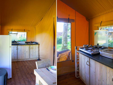 Interior de tienda safari en Slow Lodge, Camping Seasonova La Forêt, Francia, con cocina y suelo de madera.