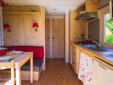 Interieur van de Gipsy wagon cabin bij Camping Seasonova La Forêt in Frankrijk met keuken en eethoek.