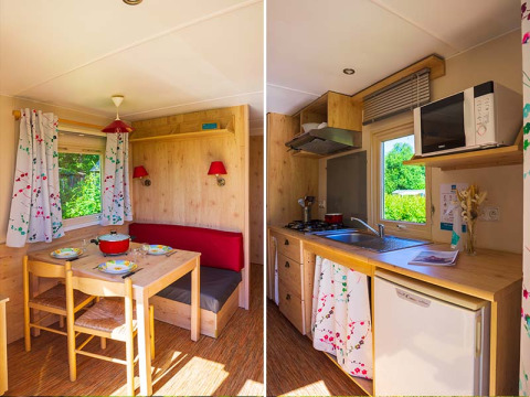 Accogliente interno della cabina Gipsy wagon al Camping Seasonova La Forêt, Francia, con zona pranzo e cucina.